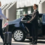 Chauffeur opening door of luxury black car for business traveler with suitcase, showcasing professional airport pickup or intercity transfer service.