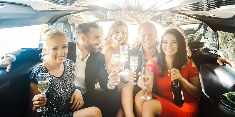 Group of friends celebrating inside luxury party limousine with champagne, highlighting premium limo service for events, nightlife, and special occasions.